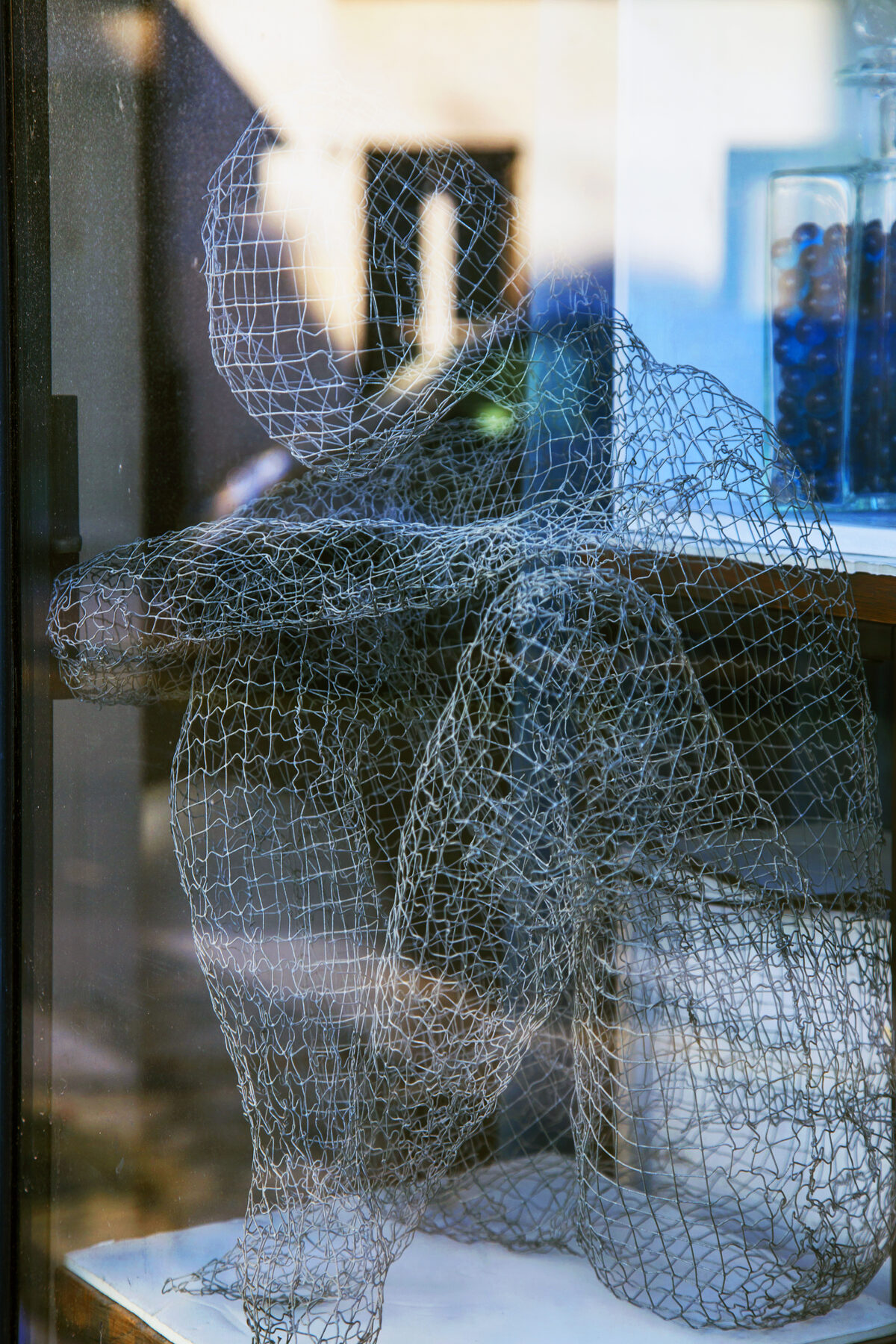 Drahtfigur hinter Fensterglas